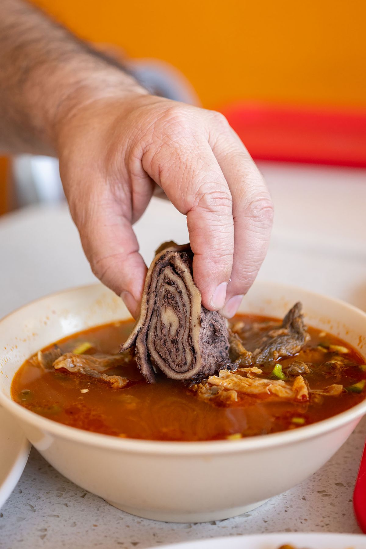 Dip bean tamal in red beef stew.
