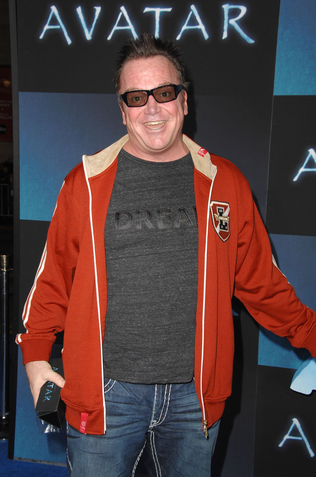 Tom Arnold in a bright red coat and 3D glasses really showing up with a smile at the Avatar premiere