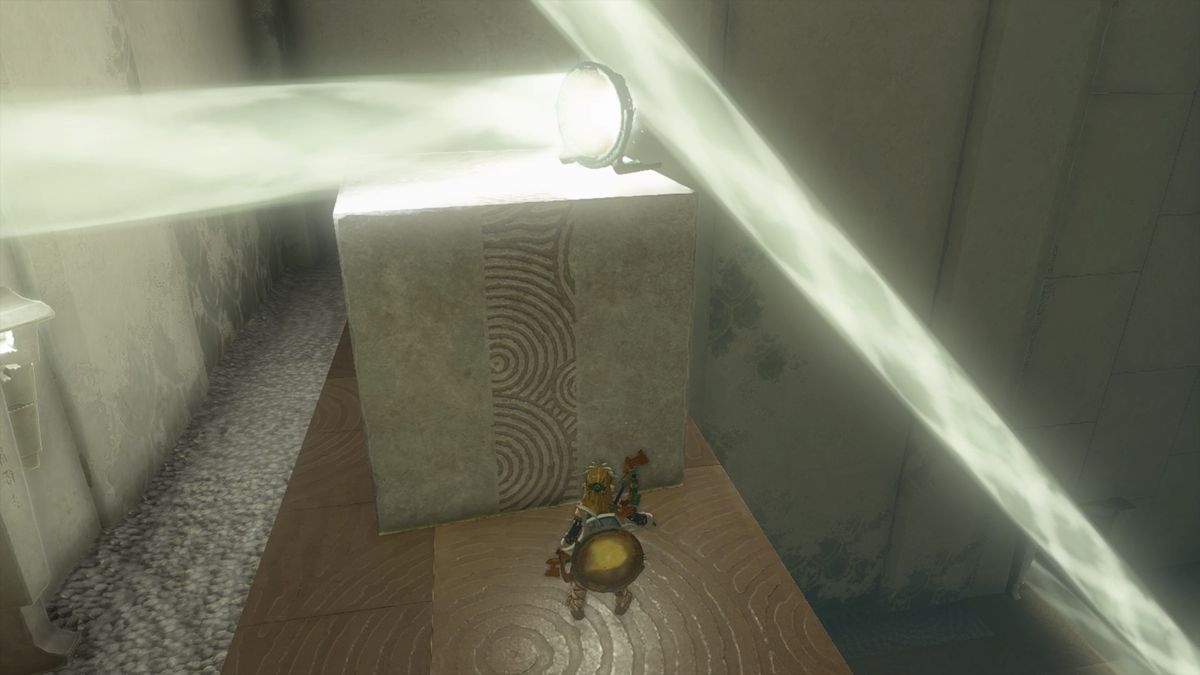 Link stands in front of a large stone cube and a mirror reflecting light in The Legend of Zelda: Tears of the Kingdom’s Rakashog Shrine