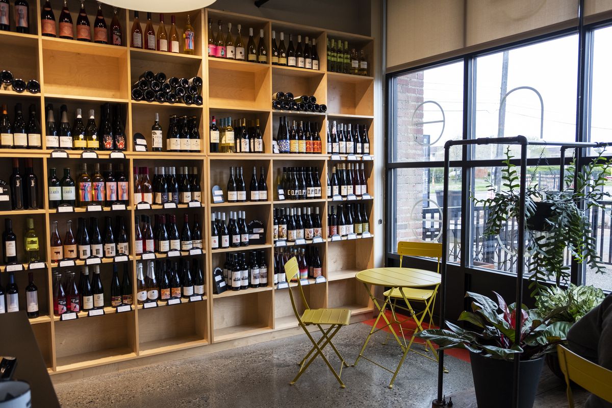 A wine shop called Side Wine with a wall-length shelving unit carrying many bottles of wine at Red Hook, a cafe based in Detroit, Michigan.