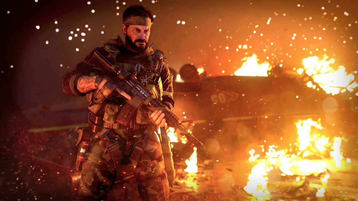 Woods stands in front of a fire in Black Ops Cold War