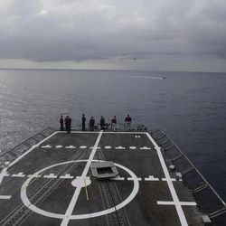 In this Thursday, Oct. 11, 2012 photo sailors stand on the flight deck as a helicopter and a RHIB boat participate in drug interdiction training exercises onboard the USS Underwood while patrolling in international waters near Panama.