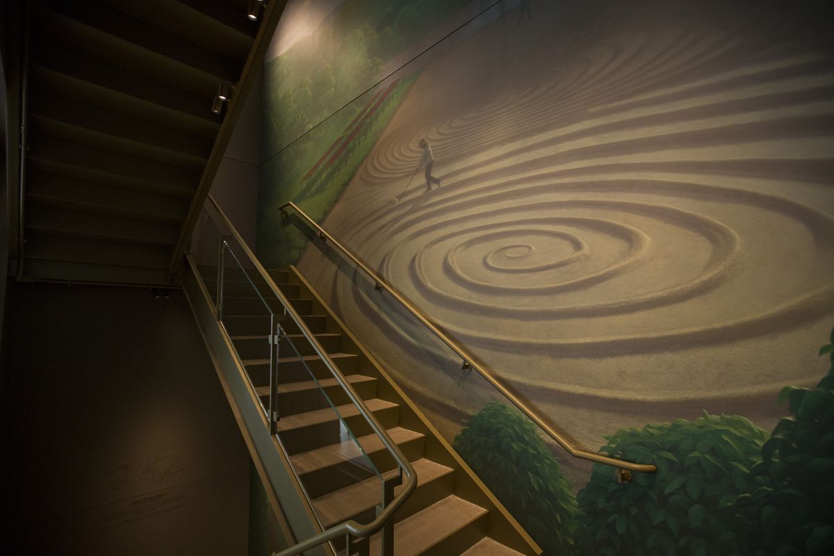 A painted green-and-brown mural of a man tending to coffee bean fields.