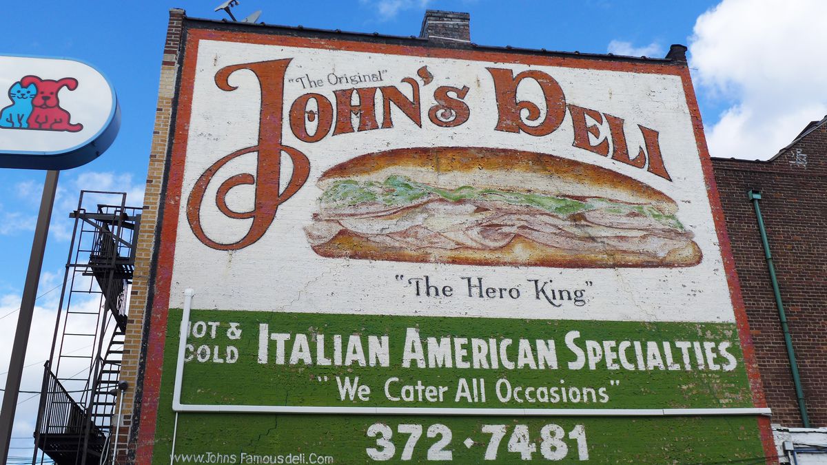 A sign painted on the entire side of the building reads John’s Deli.