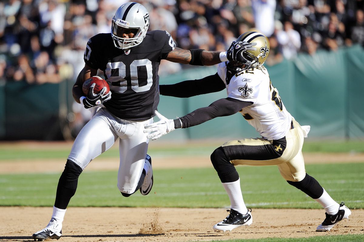 Derek Hagan #80 of the Oakland Raiders stiff arms Tracy Porter #22 of the New Orleans Saints and runs thirty five yards for a touchdown in the first quarter during an NFL pre-season football game 