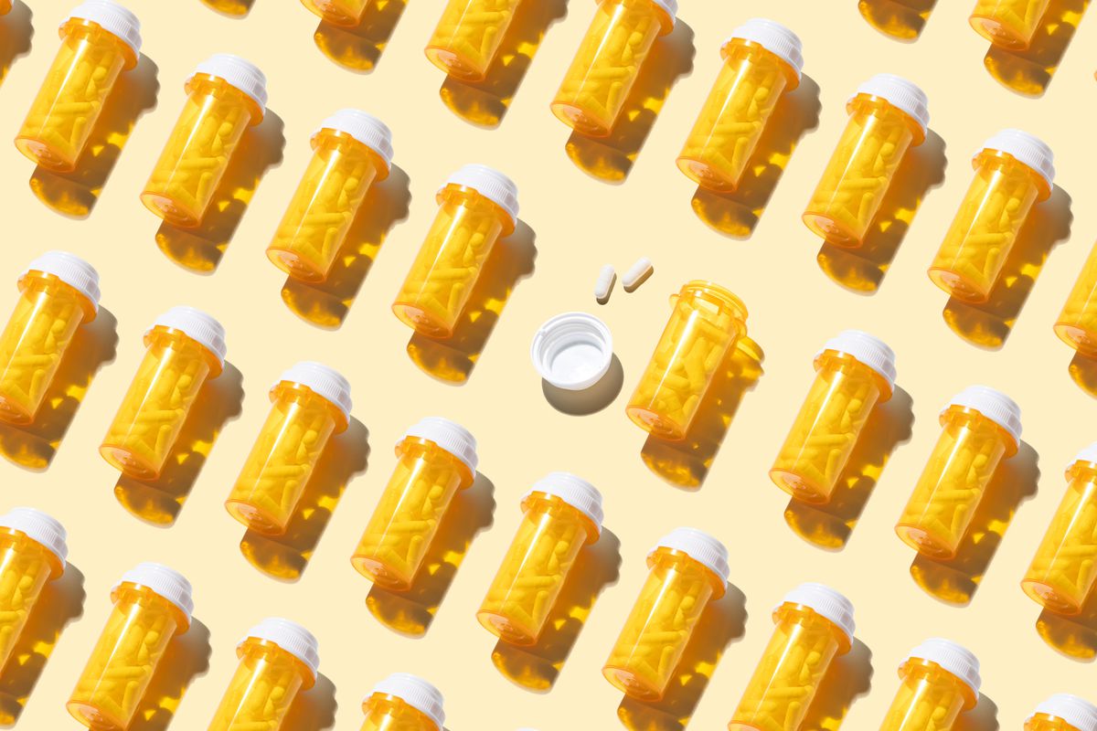 An Opened Prescription Medicine Bottle Among Many Other Sealed Bottles on Yellow Background High Angle View.