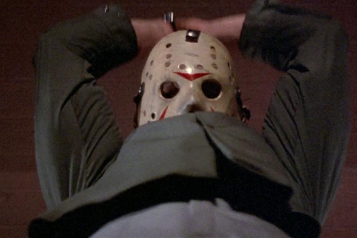 Jason Voorhees, wearing his signature hockey mask, holds both hands over his head about to slice somebody in Friday the 13th Part III.