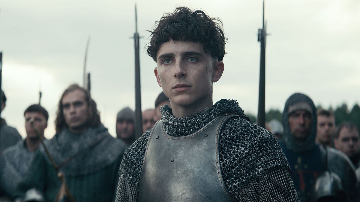 Henry (Chalamet), clad in armor, looks thoughtful.