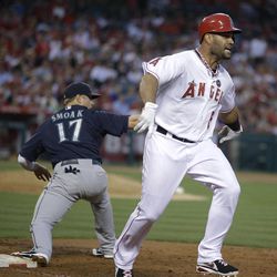 Los Angeles Angels' Albert Pujols, right, reacts after he was forced out by Seattle Mariners first baseman Justin Smoak during the third inning of a baseball game in Anaheim, Calif., Tuesday, June 18, 2013. 