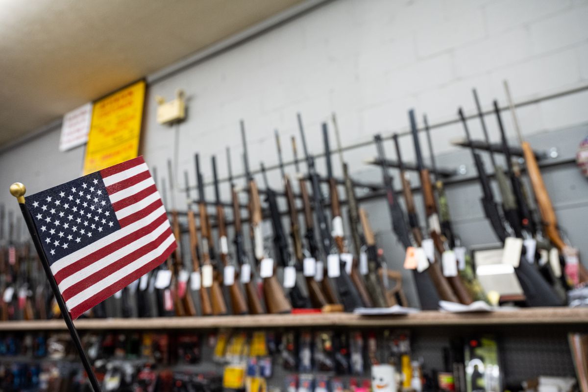 An American flag flying beside a rack of rifles for sale.