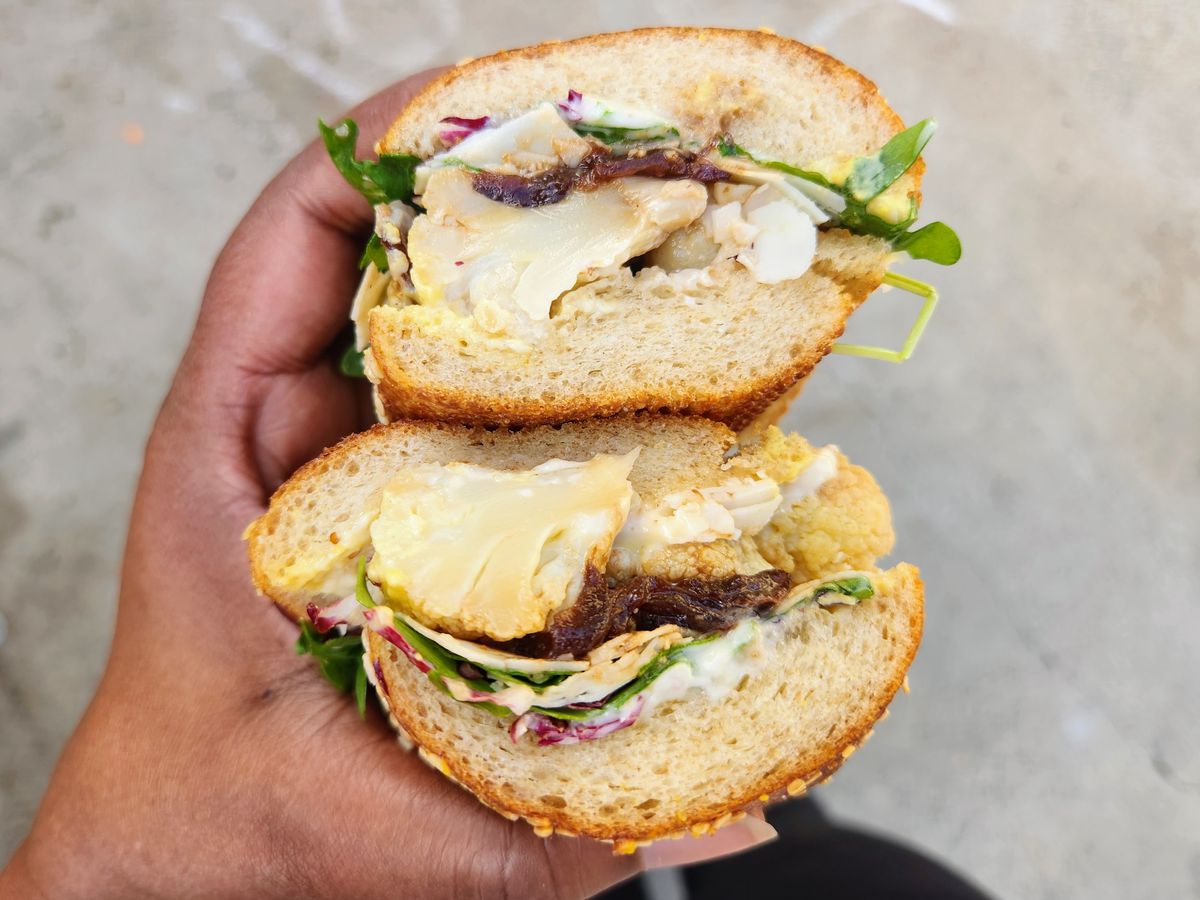 A sandwich with roasted cauliflower, cheddar, aioli, and arugula on a Bub and Grandma’s sub roll.