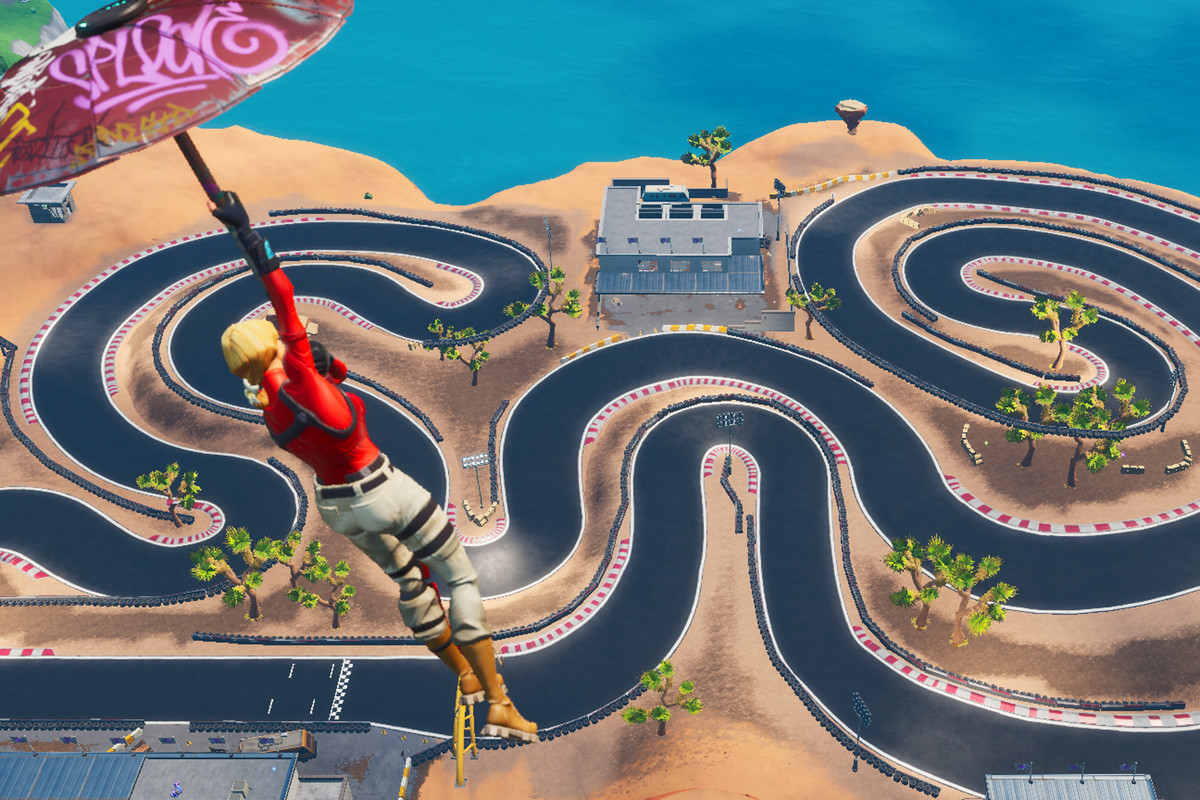 A Fortnite player glides toward a racetrack in the desert 