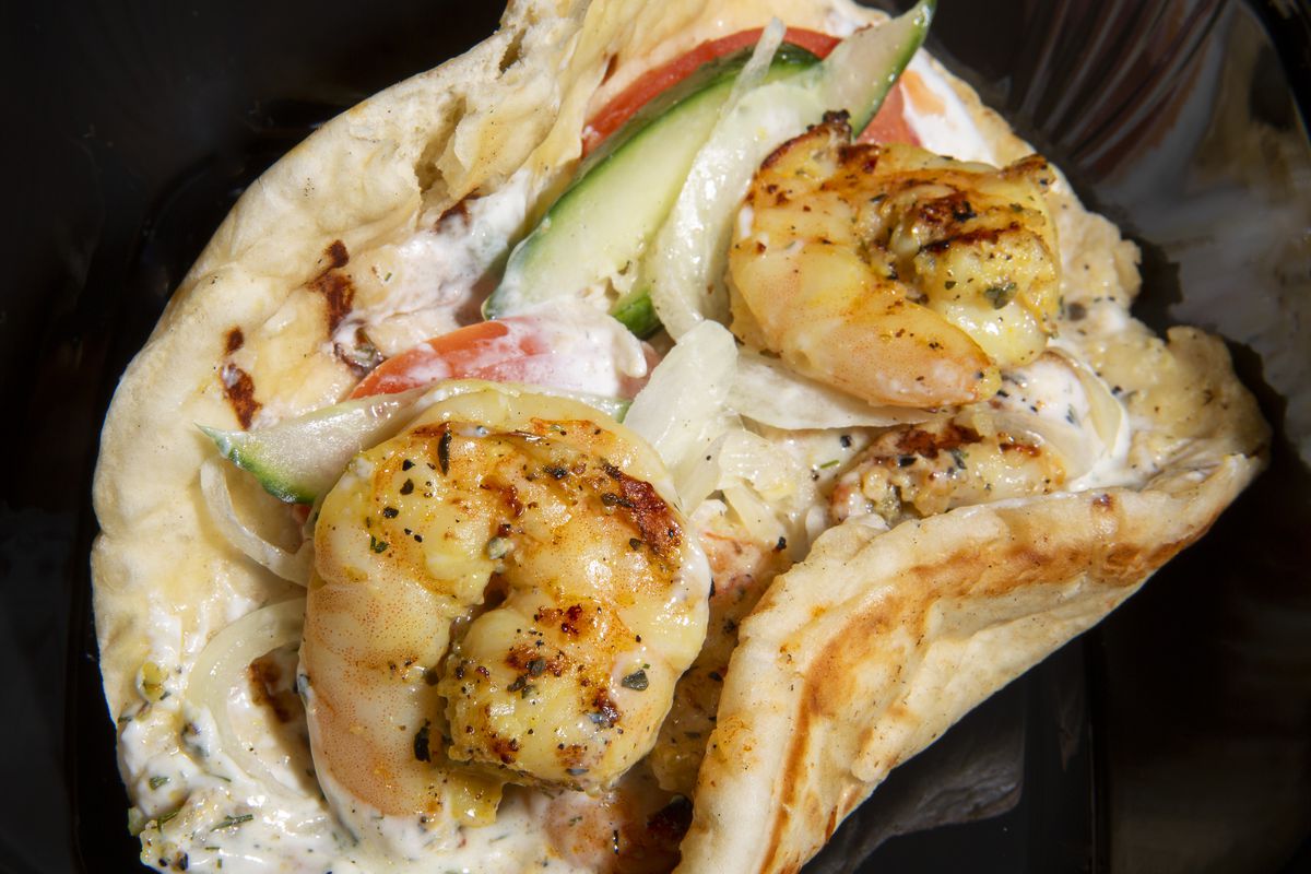 A shrimp pita with tomato and cucumber.