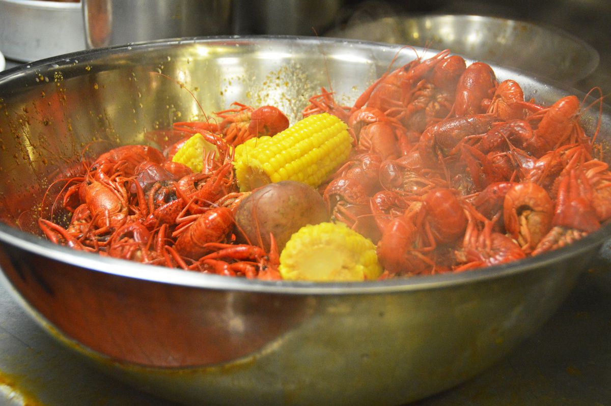 A silver bowl filled with boiled crawfish and corn.