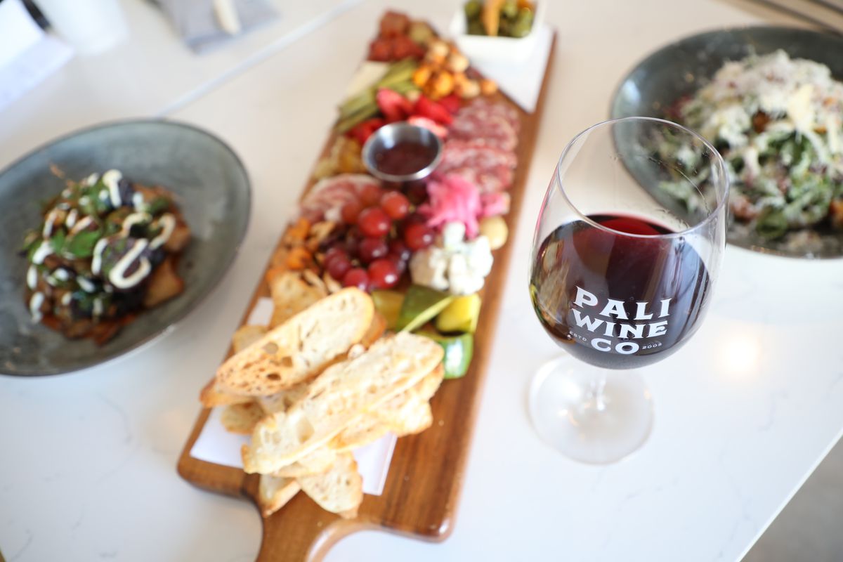 A glass of wine, salads, and a cheese and charcuterie board.