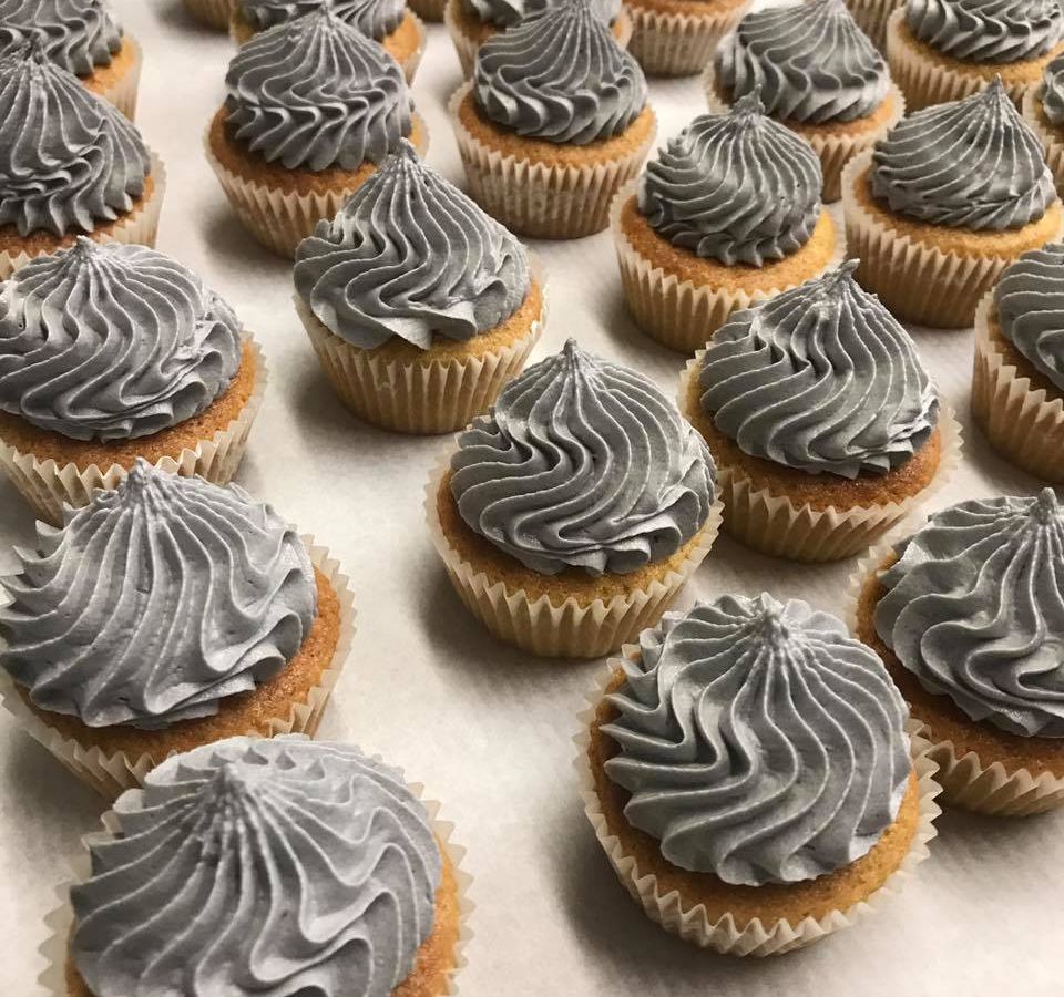 A bunch of cupcakes with gray frosting.