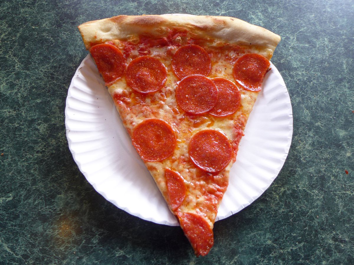 A slice of pepperoni pizza on a white paper plate.