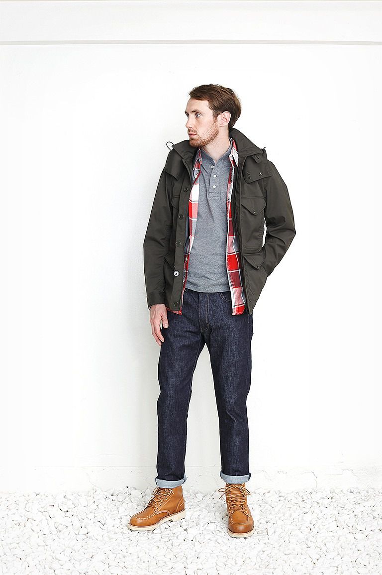 A male model wearing a jacket, flannel shirt, and jeans