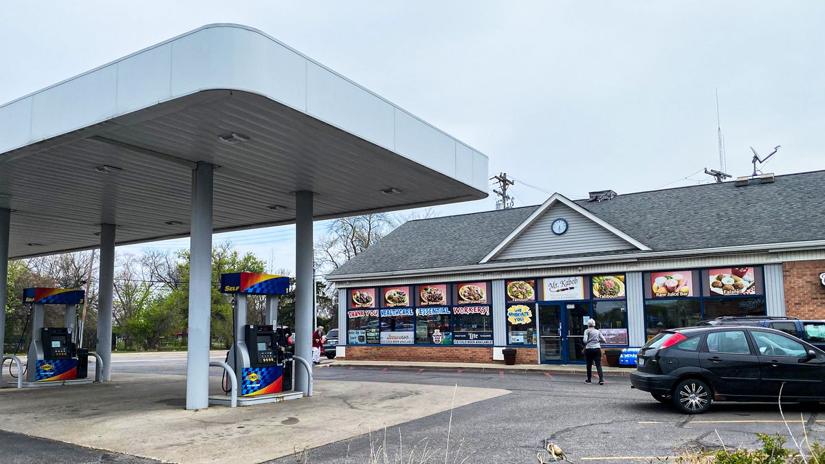 The outside of a Sunoco gas station with two visible gas pumps and a building with menus in the window.