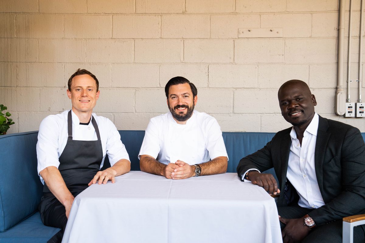 Chef Jerrod Zifchak, Aaron Bludorn, and Cherif Mbodji sit at a table at Navy Blue.