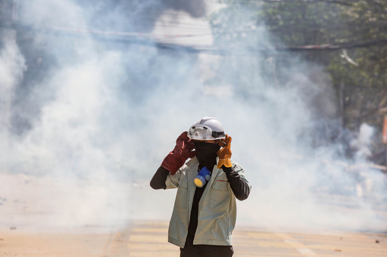 An anti military coup protester stands in the middle of teargas smoke during a demonstration in Myanmar