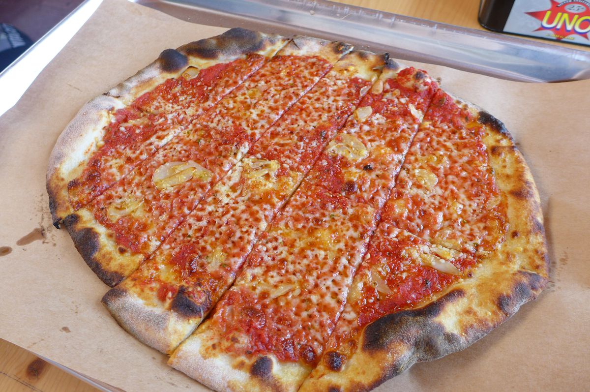 A red pizza with charred spots on the crust.