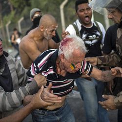 A man hit with a projectile fired by police during a protest is taken away by a military policeman and fellow demonstrators outside the Minerao stadium during a soccer Confederations Cup match between Japan and Mexico in Belo Horizonte, Brazil, Saturday, June 22, 2013. Thousands of anti-government demonstrators again took to streets in several Brazilian cities Saturday after the president broke a long silence to promise reforms.