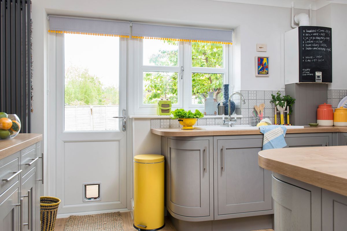 A gray kitchen with a bright yellow trash can. 