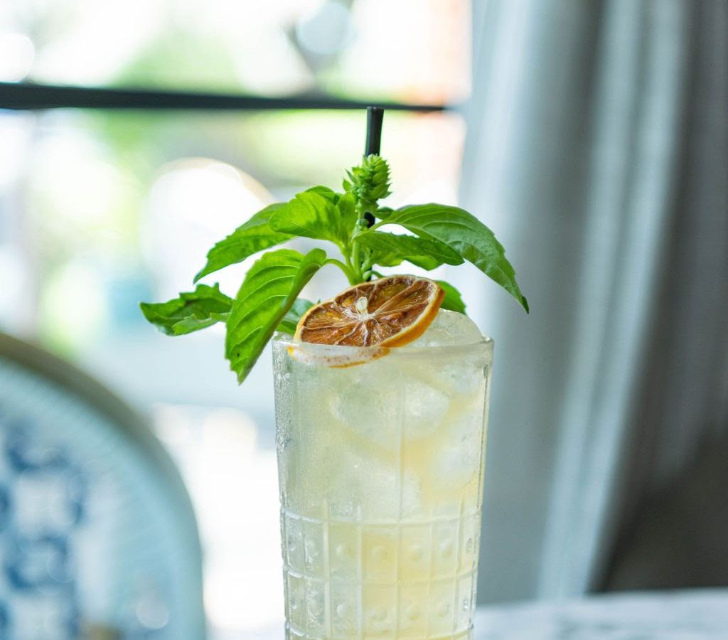 A cocktail topped with a lemon garnish and sprig of mint.