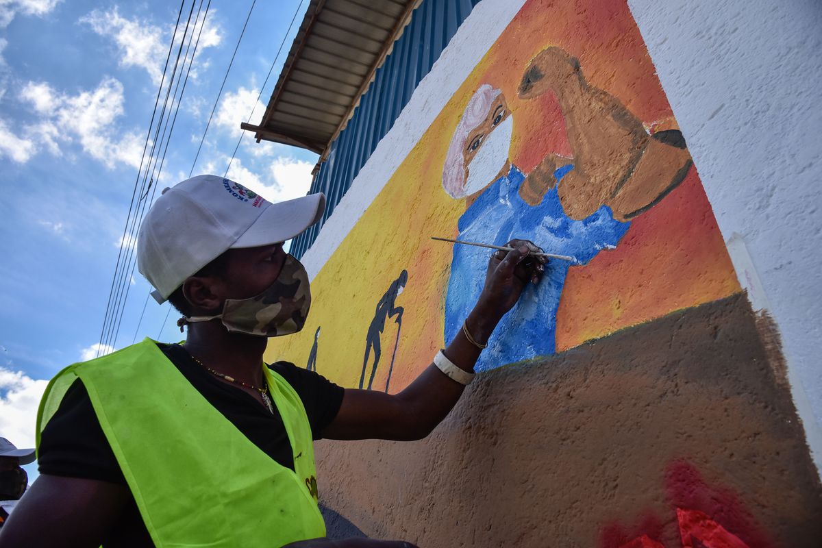 An artist paints a mural of Covid-19 containment measures on a wall in Nakuru, Kenya.