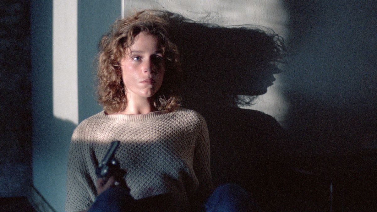 Frances McDormand holds a gun and extends into a shadow in Blood Simple