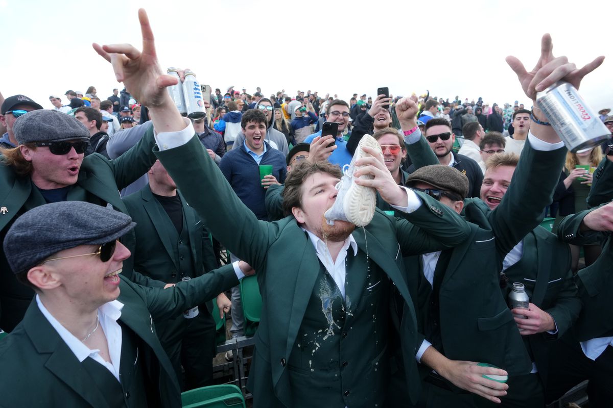 Fans drink from a shoe in the stands on the 16th hole during the 2024 Phoenix Open at TPC Scottsdale.