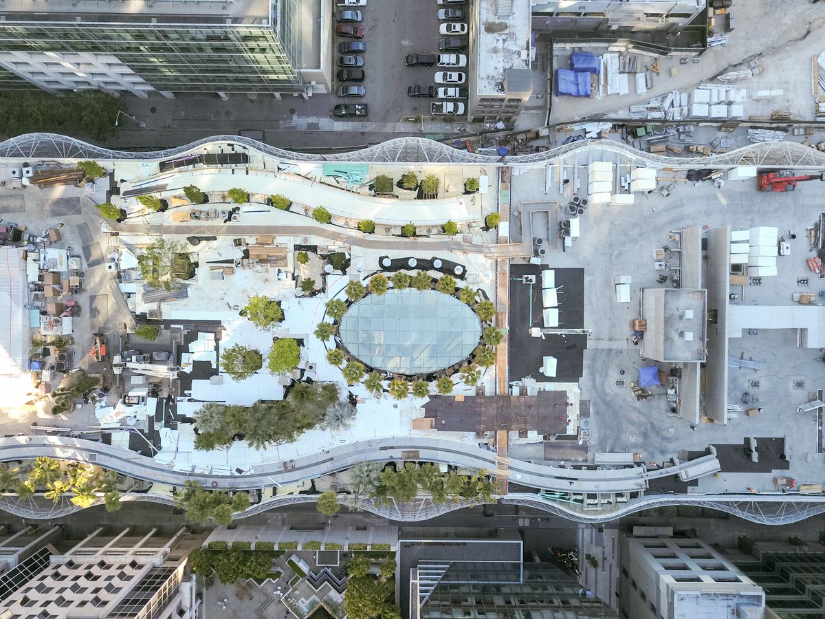 Arial shot of the Transbay Transit Center from above, showing wavy curtain work, trees, and park under construction. 