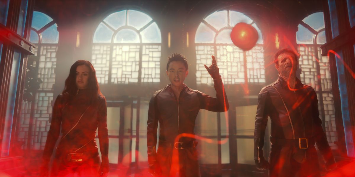 Jayme, Ben, and Alphonso surrounded by eerie red light, while wearing red spandex suits