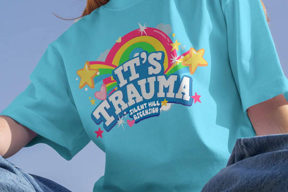 A light blue T-shirt that says “It’s Trauma” and “Silent Hill: Ascension” on the front. It’s surrounded by rainbows and stars.