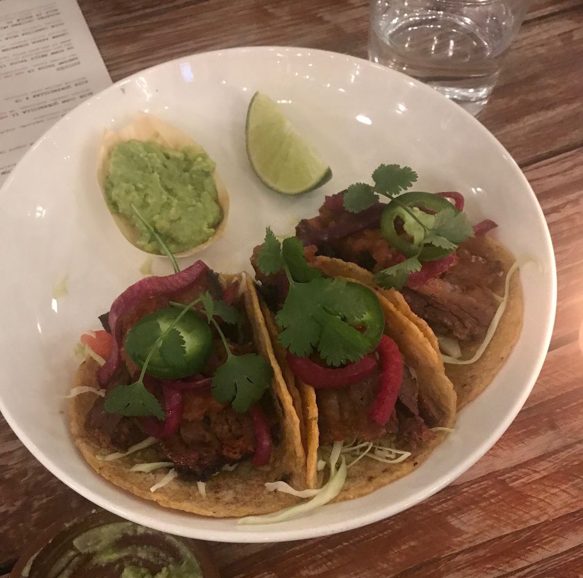 A trio of tacos in a white bowl.
