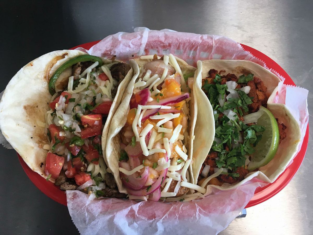 A red food basket with three tacos.