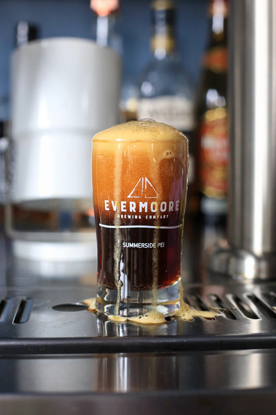 An overflowing beer beneath a tap, with the name Evermore on the glass.
