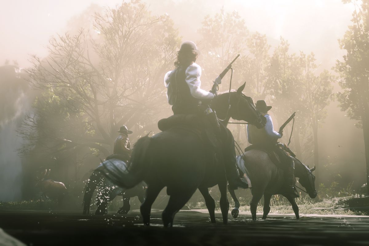 Three characters ride on horseback through a stream in a screenshot from Red Dead Redemption 2