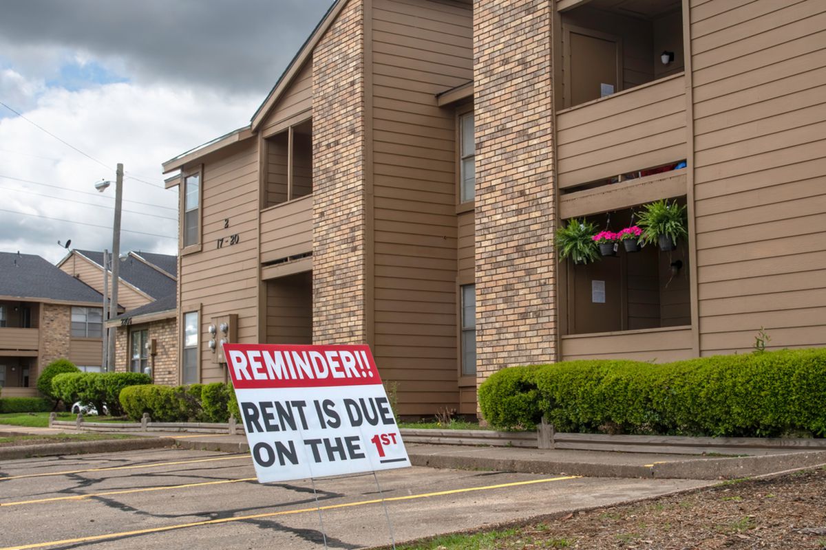 A sign in the parking lot of an apartment complex reminds renters that “Rent is due on the 1st.”