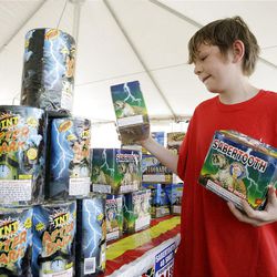 At left, Alan Baker stocks the shelves at a TNT fireworks stand in Salt Lake County on Thursday. Above, signs in the stand remind patrons of the restrictions regarding aerial fireworks.