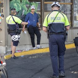 Officers Wilson Silva, right, and W. Sackett talk to a person at the Gateway Inn, located next to a new police bike patrol substation on North Temple in Salt Lake City on Wednesday, July 25, 2018. Police get calls from the inn often, according to Salt Lake City Police Sgt. Robert Ungricht.