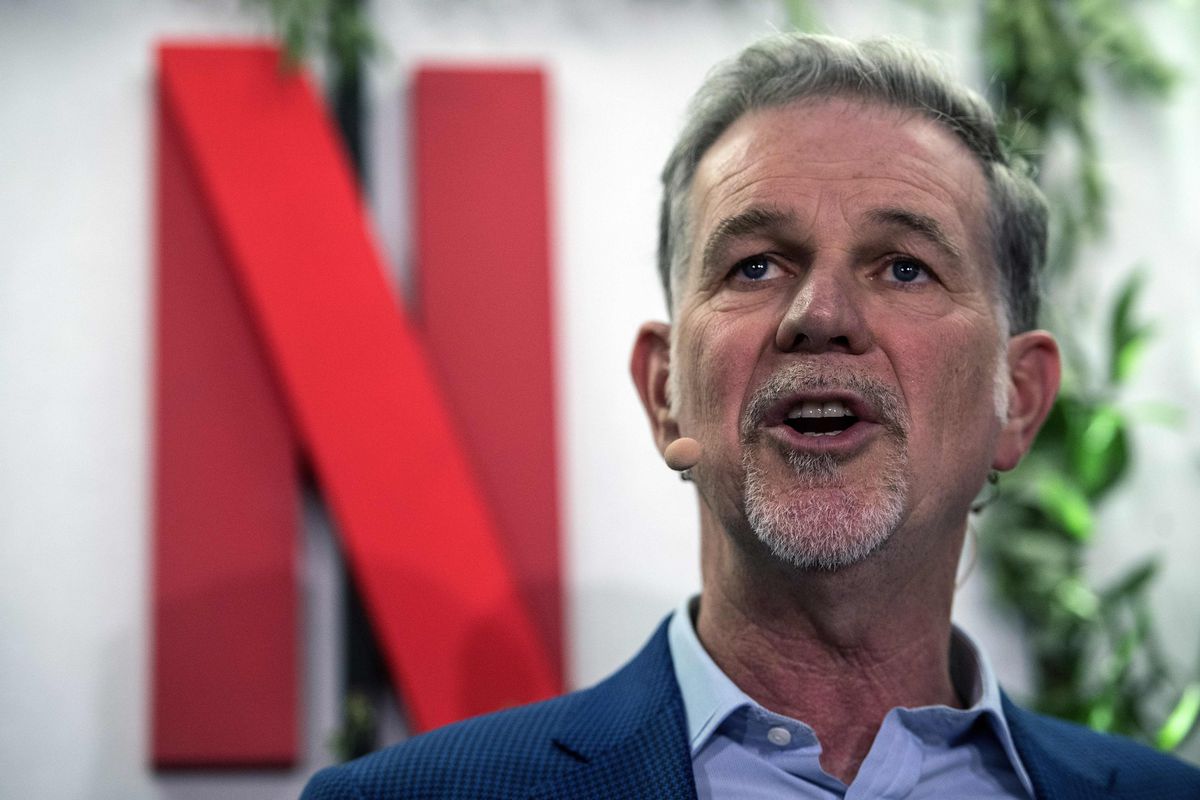 An image of Netflix CEO Reed Hastings speaking, the logo for Netflix appears behind him.