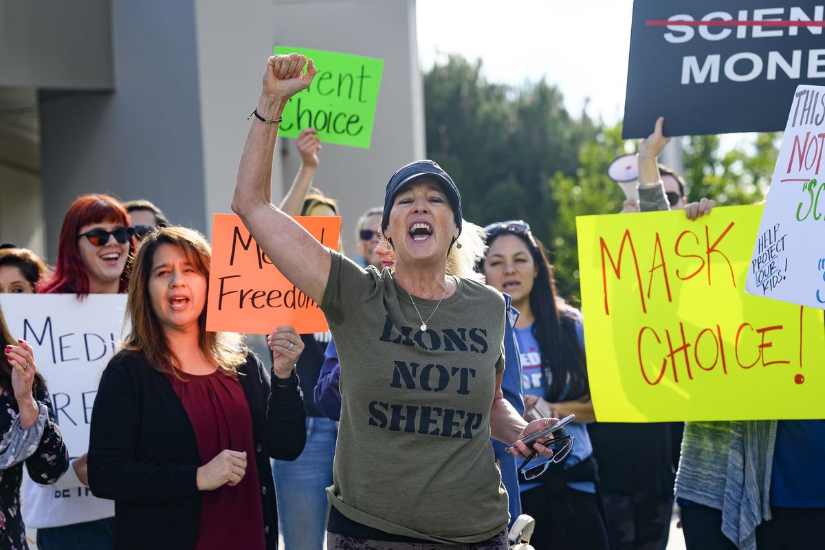 Protestors hold signs like “Mask choice” and “Mask freedom” in a protest.