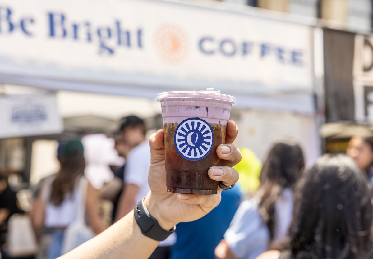 A person holds a beverage container from Be Bright Coffee.