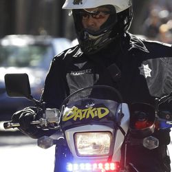 A San Francisco Police Officer with a Batkid sign on his bike waits for the arrival of Miles Scott, dressed as Batkid, in San Francisco, Friday, Nov. 15, 2013. San Francisco turned into Gotham City on Friday, as city officials helped fulfill Scott's wish to be "Batkid." Scott, a leukemia patient from Tulelake in far Northern California, was called into service on Friday morning by San Francisco Police Chief Greg Suhr to help fight crime, The Greater Bay Area Make-A-Wish Foundation says.