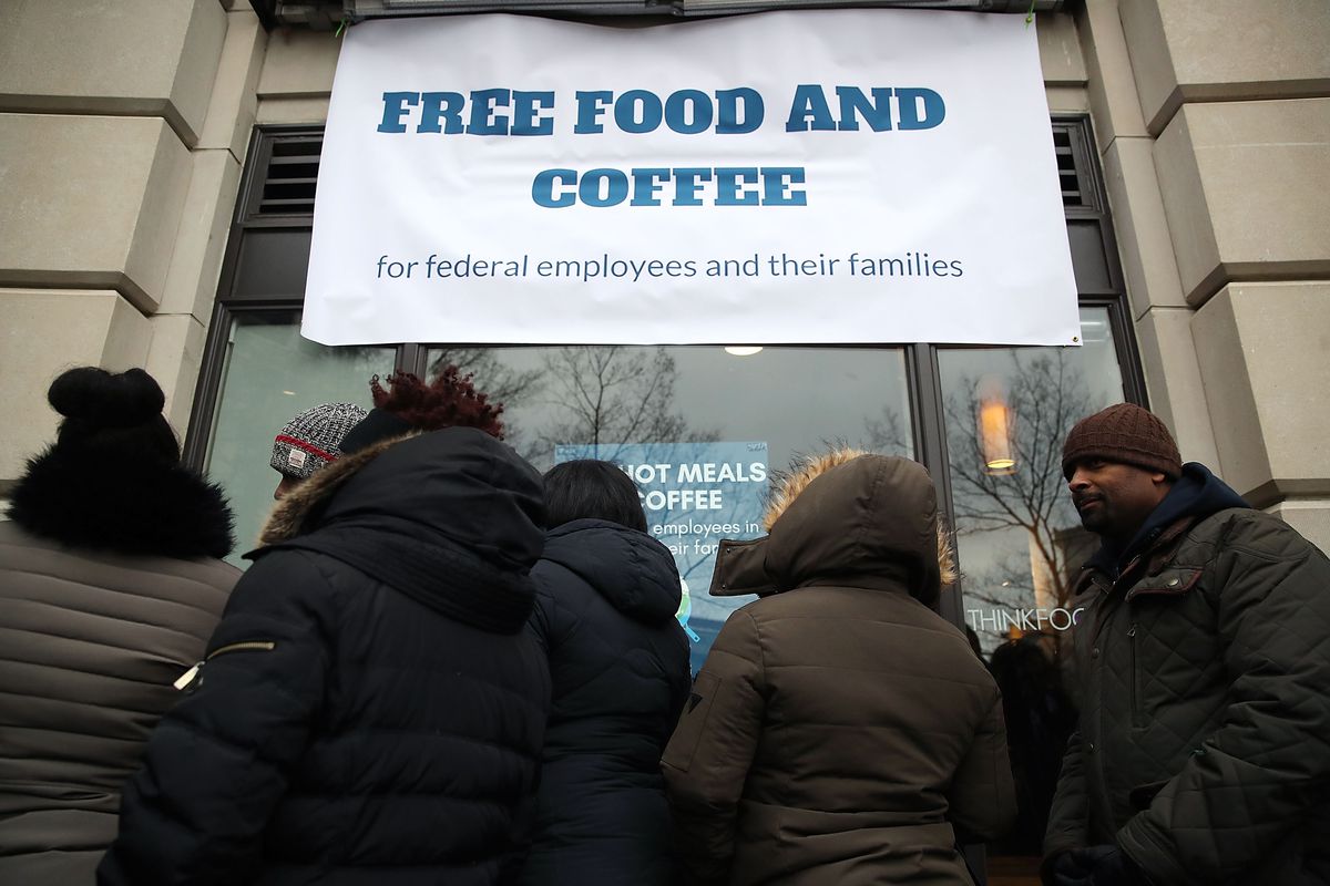 People line up at a pop-up eatery under a sign reading, “Free food and coffee for federal employees and their families.”