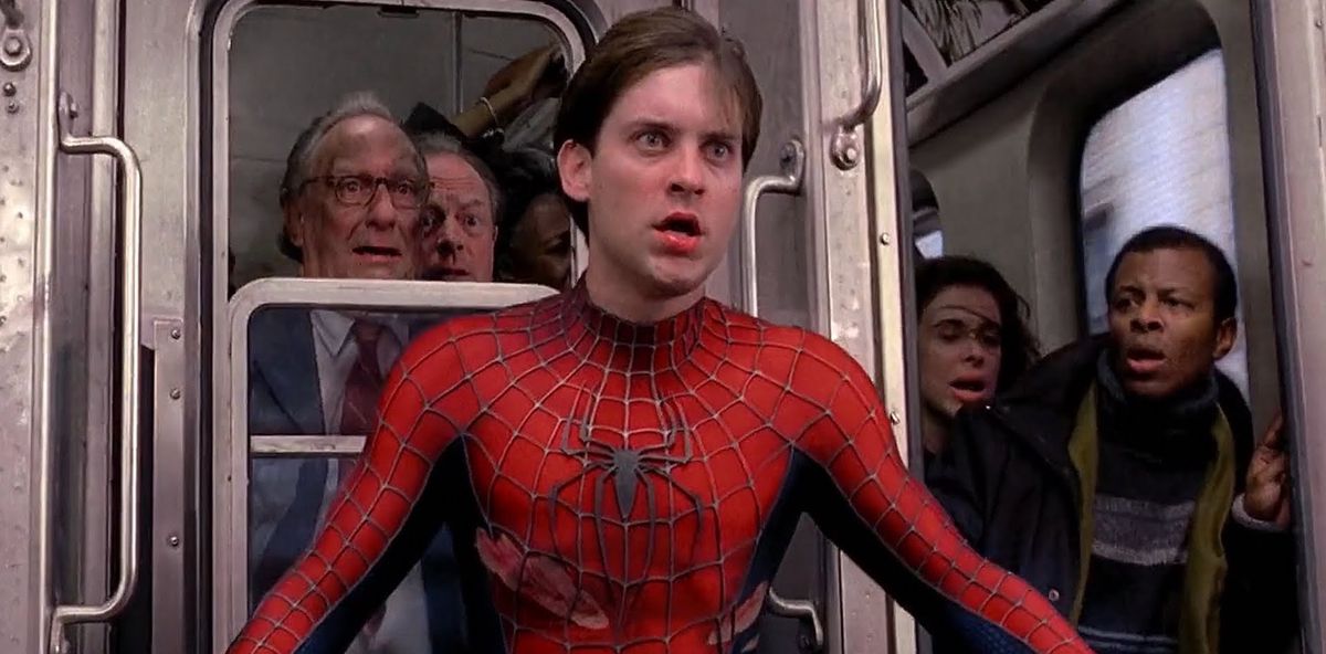 A bloodied, unmasked Spider-Man (Tobey Maguire) stands between Doc Ock and civilians on a train in Spider-Man 2