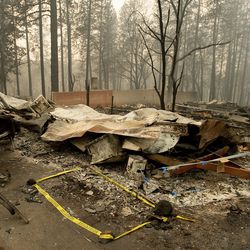 FILE - In this Wednesday, Nov. 14, 2018 file photo, tape marks a spot where sheriff's deputies recovered the body of a Camp Fire victim in Paradise, Calif. Rain in the forecast starting Wednesday, Nov. 21, could aid crews fighting Northern California's deadly wildfire while raising the risk of debris flows and complicating efforts to recover remains. The National Weather Service has issued a flash flood watch Wednesday for the decimated town of Paradise and nearby communities. (AP Photo/Noah Berger, File)