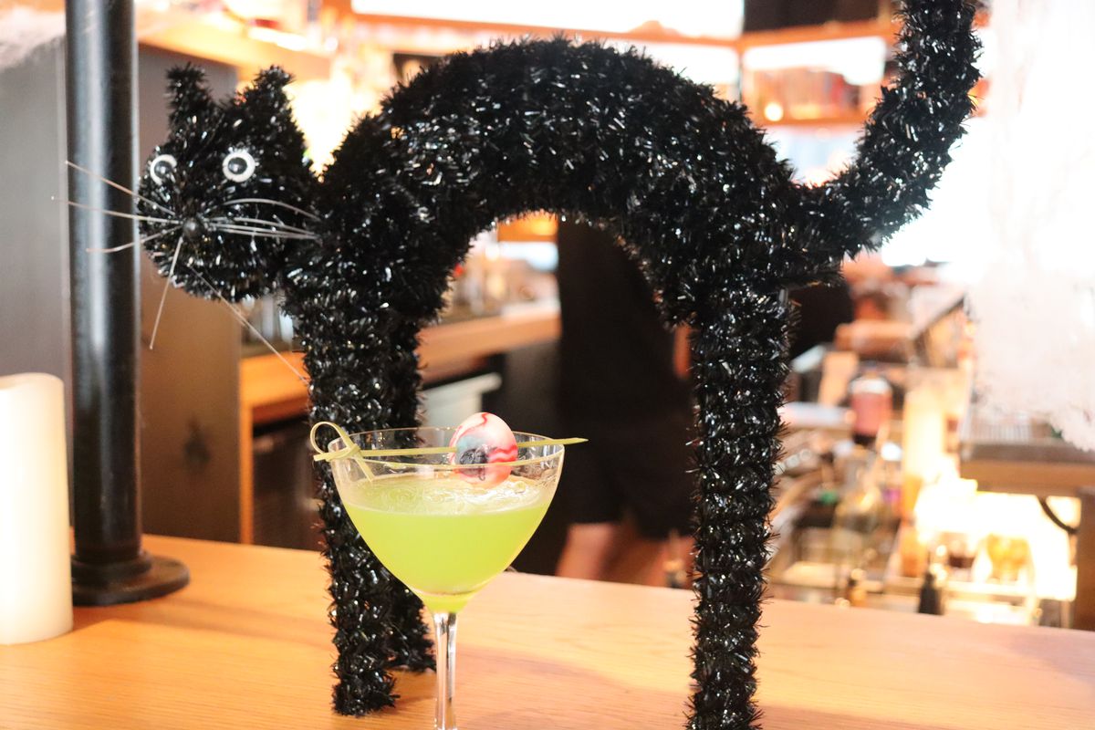 A black cat toy and a cocktail with a fake eyeball in it.